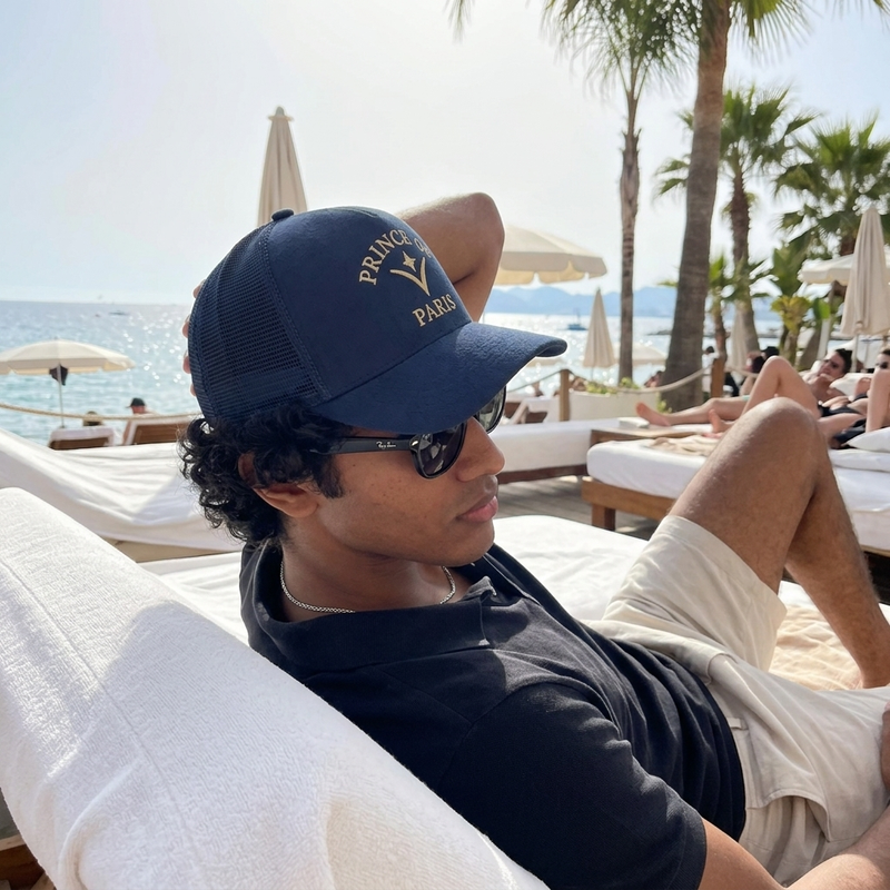 Beach club lounging wearing Prince of Paris Navy cap
